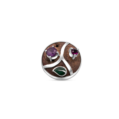 A pendant crafted from Brazil nut hedgehog material, with amethyst and garnet stones, and a swirling silver design inlaid into the warm, textured background.