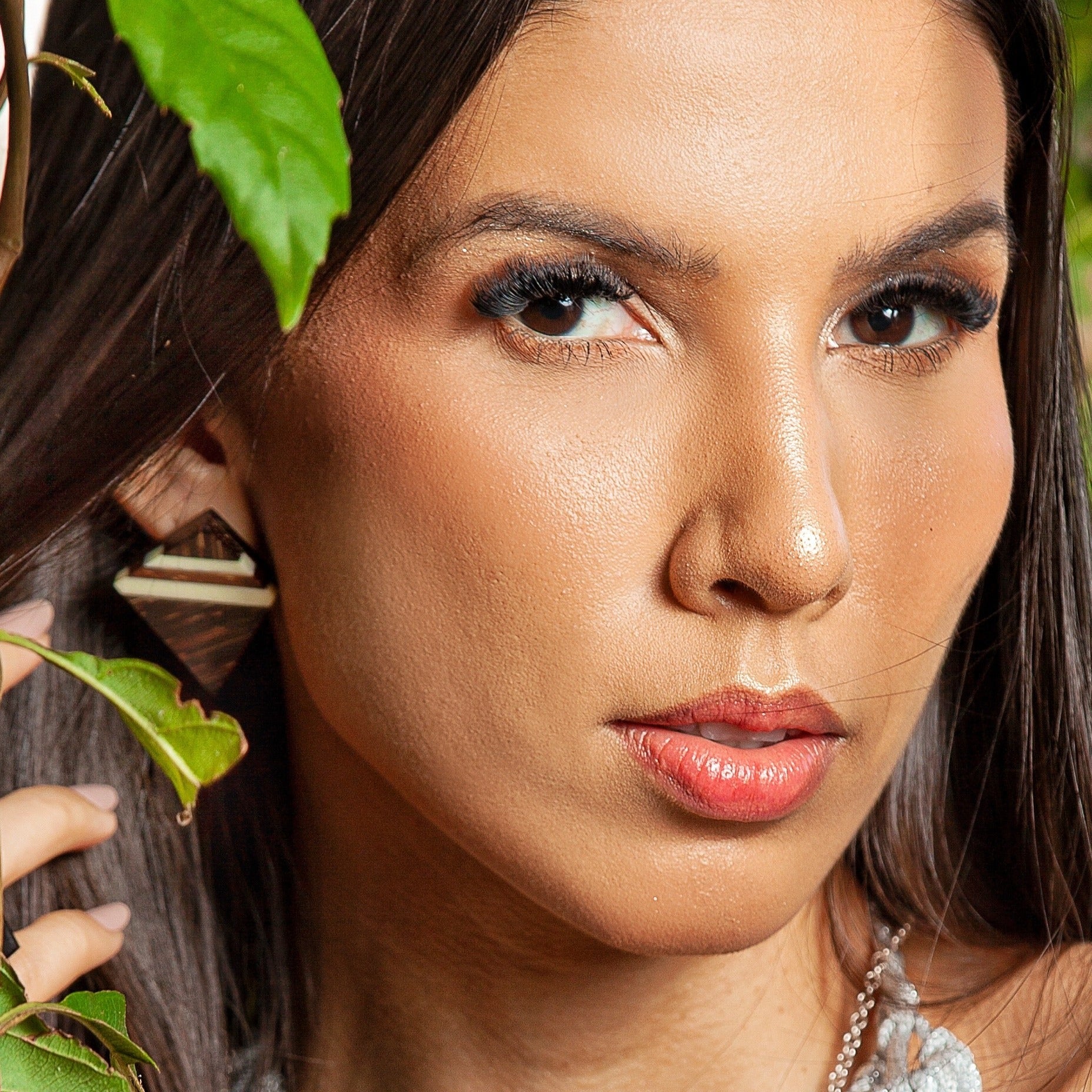 The image features a close-up of a woman wearing unique earrings. These earrings are handcrafted with attention to sustainability, using recycled bone as the primary material, complemented by 925 sterling silver for the backing. This combination of upcycled elements and precious metal exemplifies modern eco-friendly jewelry design.